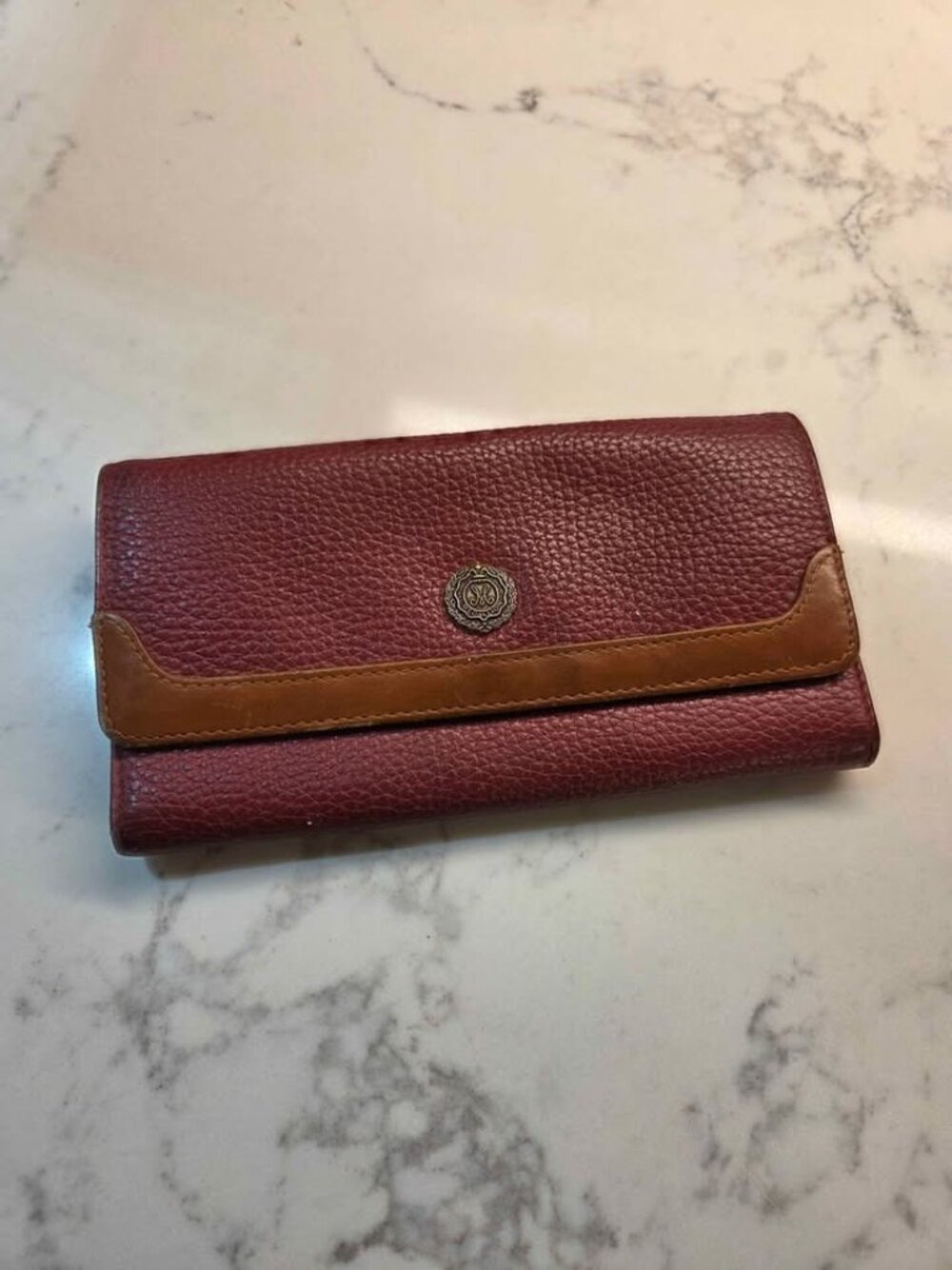 vintage dark red pebbled leather wallet featuring a tan trim and a central round